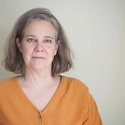 Foto von Sabine Musseleck in einem orangefarbenen Oberteil