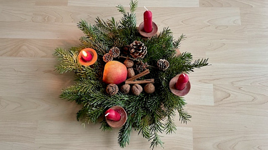 Foto meines Adventskranzes 2025 mit roten Kerzen, Apfel, Nüssen, Zapfen und Zimtstangen
